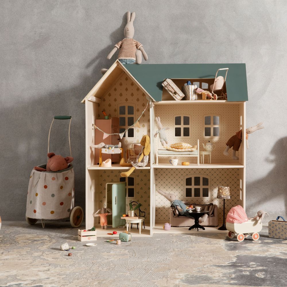 Maileg wooden dollhouse filled with miniature furniture and rabbit toys in a cosy, vintage-style setting