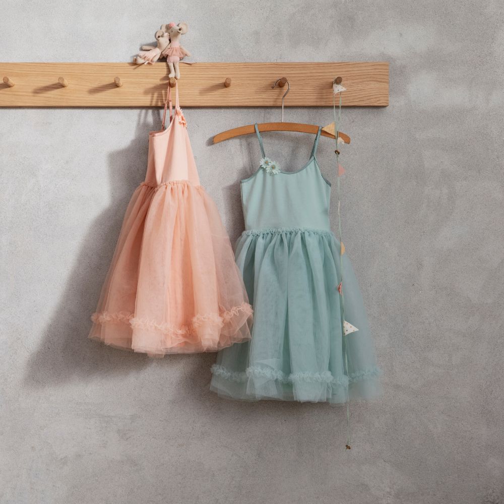 Two Maileg childrenβs tulle dresses in peach and teal hanging on wooden pegs, with toy mice dressed as ballerinas perched above