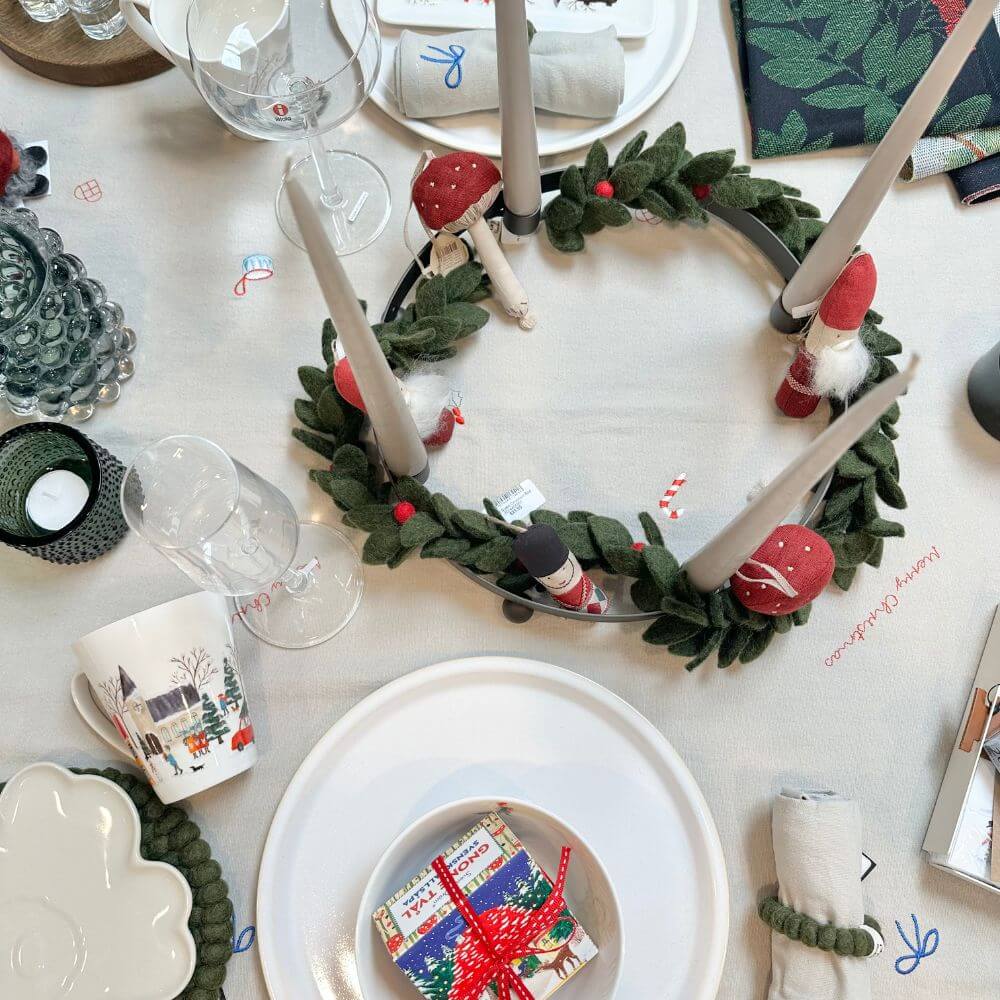 Decorative Christmas wreath with candles on a table setting.