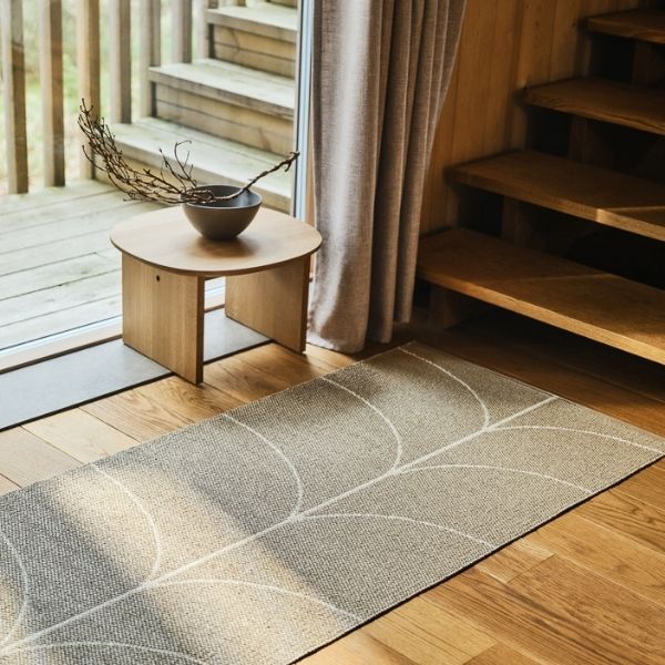 Pappelina Leif Rug on a wooden floor with a small table and decorative elements.